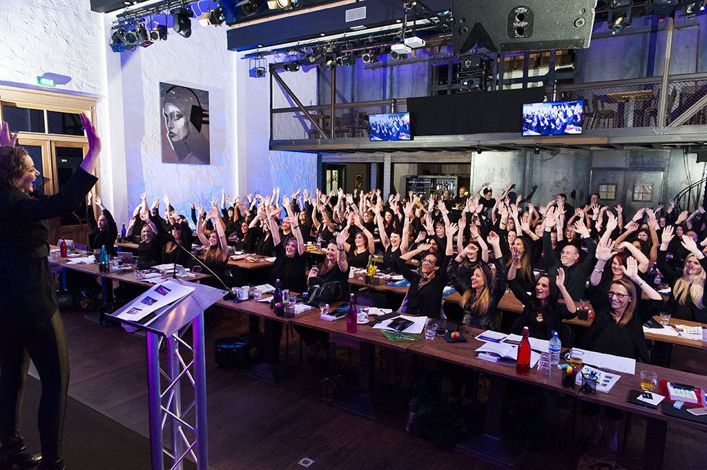 Rob Cartwright London corporate event photographer MAC makeup cosmetics beauty teambuilding action hands up conference meeting ELC Amsterdam audience fun laughing
